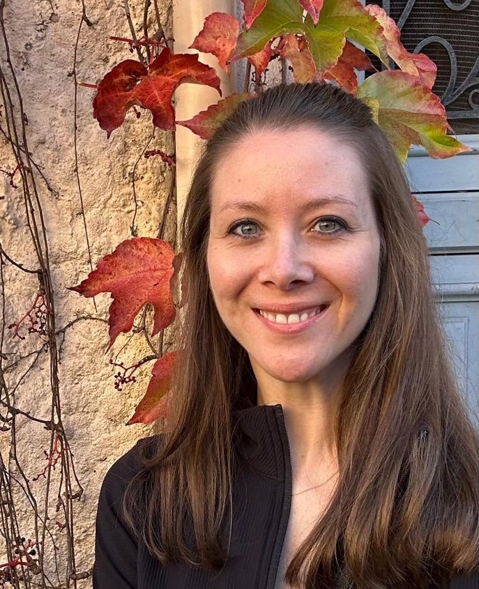 Leah Horgan, health coach and founder of Forward Momentum, smiling outdoors with autumn foliage